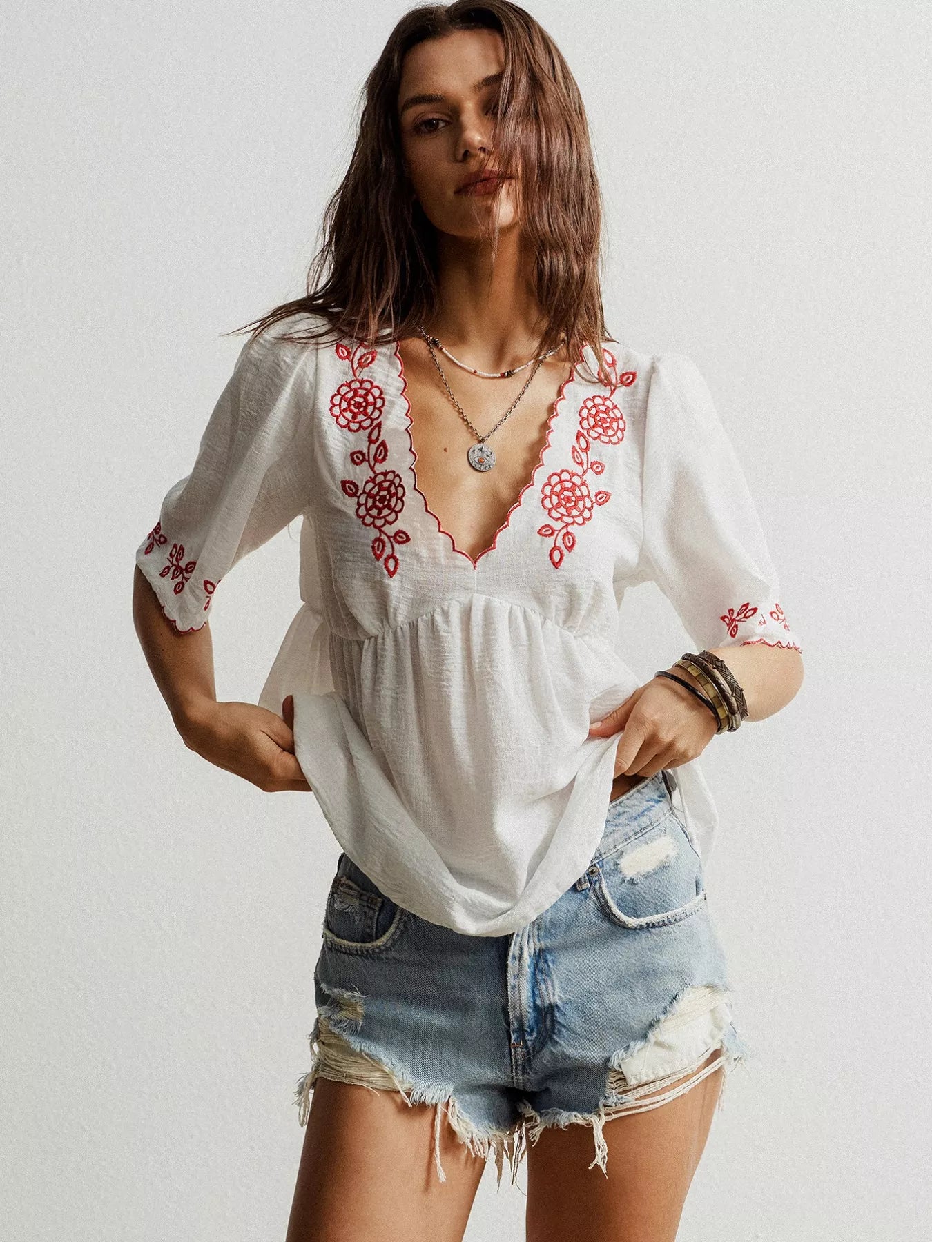 woman wearing an embroidered v neck blouse with floral detail