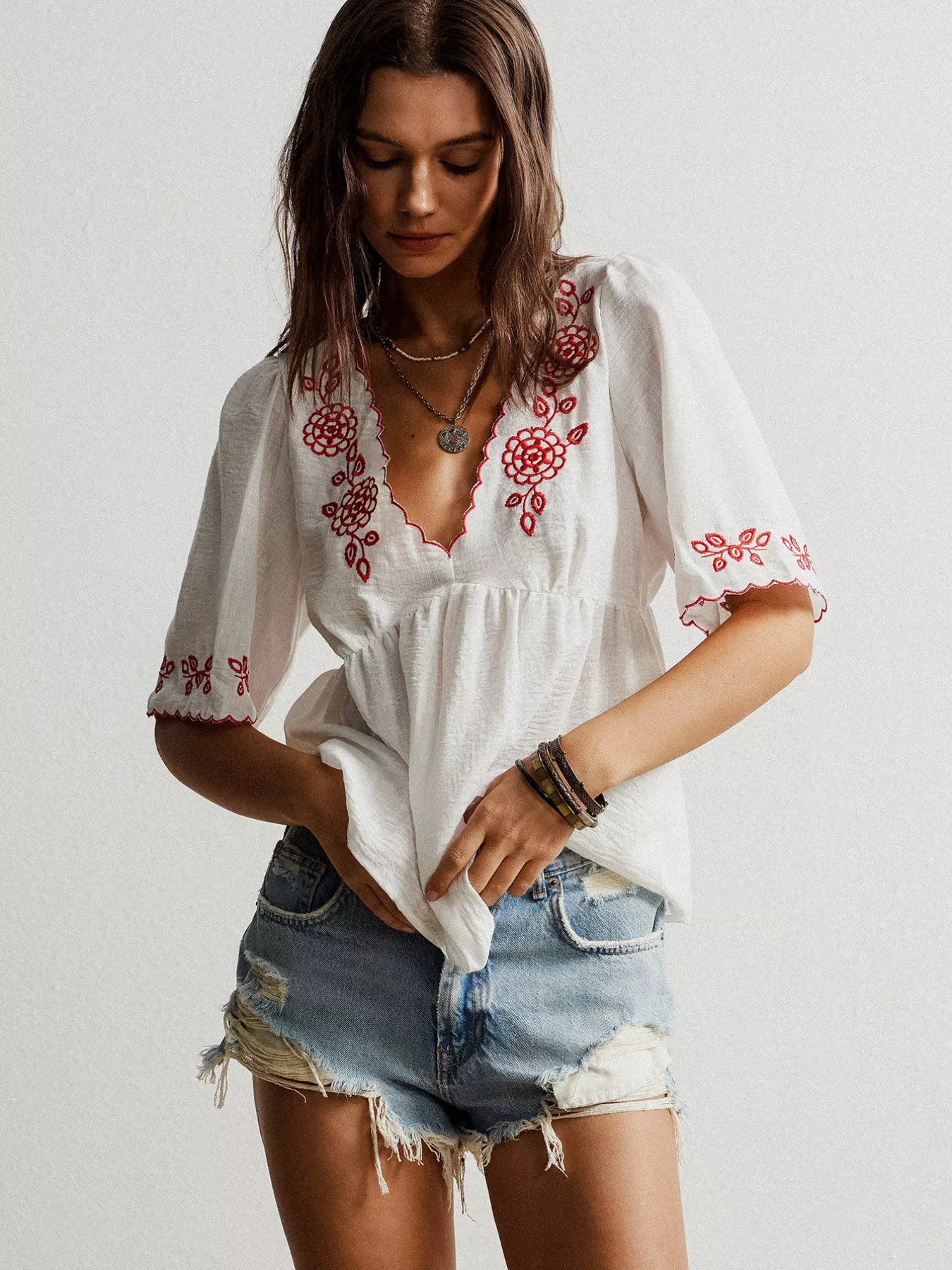 woman wearing a flowy v neck blouse with floral embroidered detail