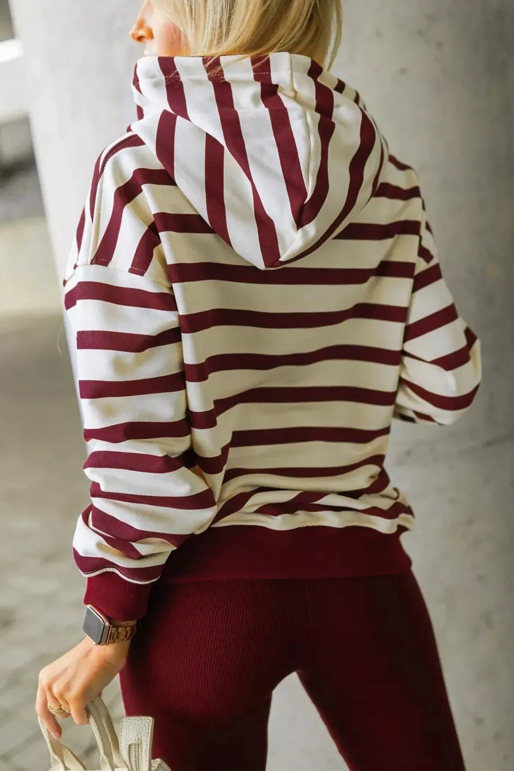 woman wearing a hooded maroon and white stripe hoodie and leggings set