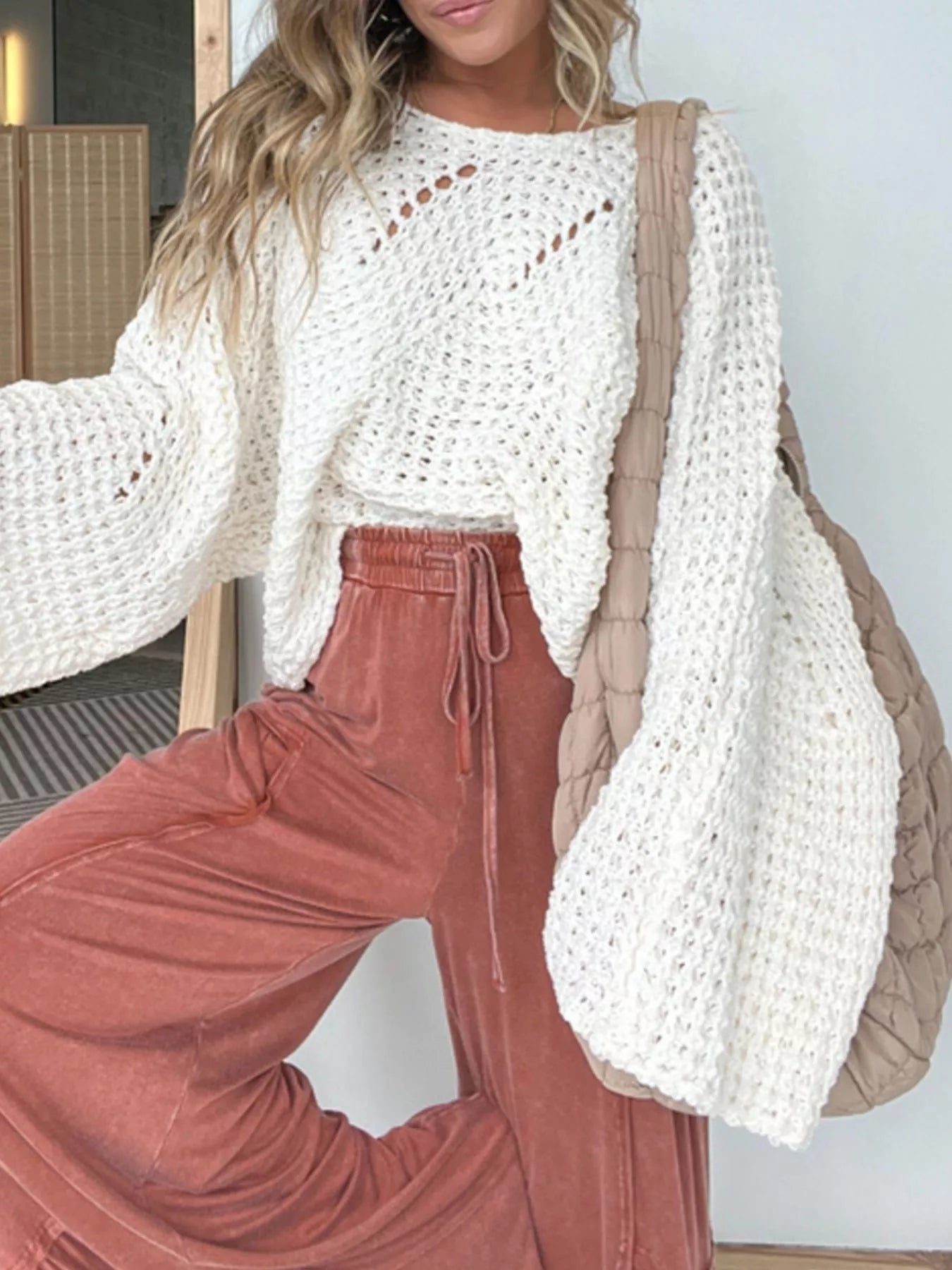 woman wearing a white open knit bat wing sweater