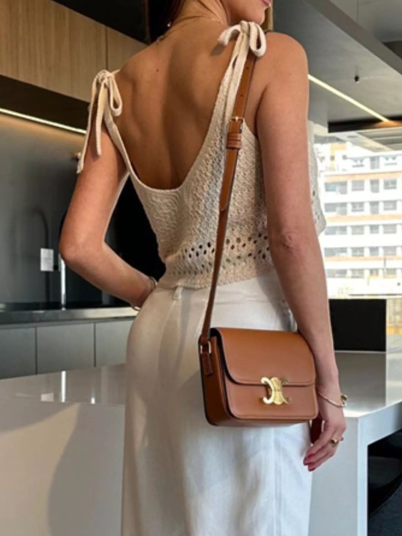 woman showing the back and bowtie detail on a boho crochet cami top